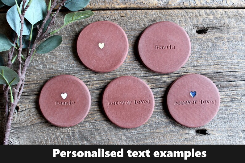May include: Five terracotta coasters with personalized text examples. The coasters feature the words "Bonnie", "forever loved", and a heart symbol.