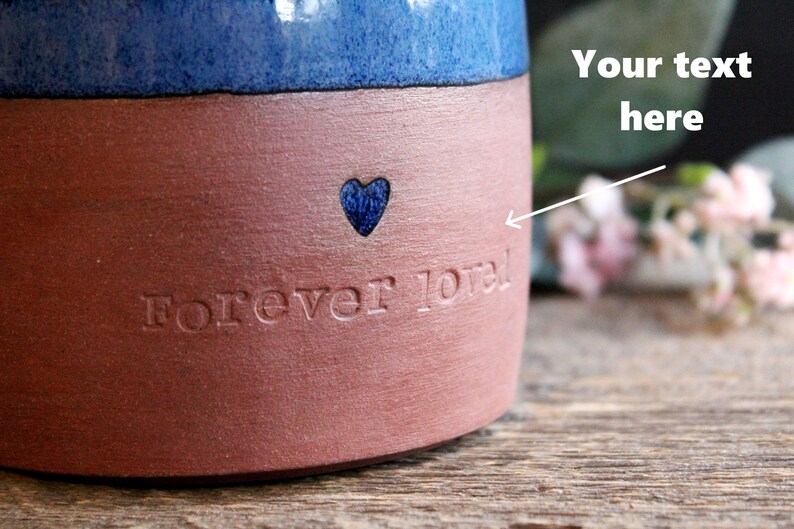 May include: A red and blue ceramic mug with the words "Forever loved" and a blue heart etched into the side.