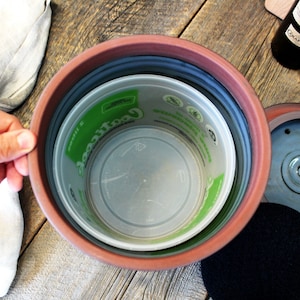 Puede incluir: Un contenedor de compost de terracota con una tapa extra&iacute;ble y un filtro de carb&oacute;n vegetal negro. El contenedor tiene un forro de pl&aacute;stico con una etiqueta verde que dice "Cool Compost".