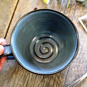 Puede incluir: Una taza de cer&aacute;mica azul con un dise&ntilde;o en espiral en el interior. La taza est&aacute; vac&iacute;a y tiene un asa.