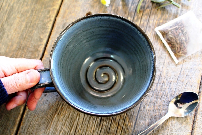 Puede incluir: Una taza de cer&aacute;mica azul con un dise&ntilde;o en espiral en el interior. La taza est&aacute; vac&iacute;a y tiene un asa.