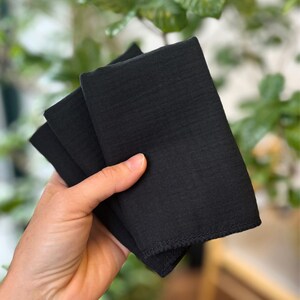 May include: A set of three black microfiber cloths folded together. The cloths are soft and absorbent, making them ideal for cleaning surfaces.