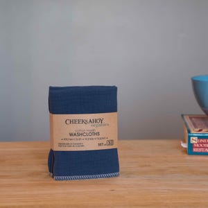 May include: A set of three blue cotton muslin washcloths, packaged and labeled "Cheeks Ahoy Organics Cotton Muslin Washcloths - Kitchen Cloth - Hankie - Napkin - Set of 3 - Handmade in Canada - Fait &agrave; la main au Canada."