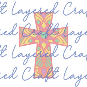 May include: A pink, yellow, and green mandala cross with a floral design. The cross is layered and has a multi-colored pattern.
