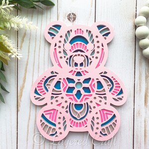 May include: Pink wooden bear cutout with intricate blue and pink mandala designs. The bear is a layered craft.