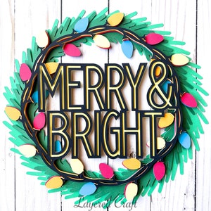 Pu&ograve; includere: Una ghirlanda natalizia di carta a strati con le parole "MERRY & BRIGHT" in nero e oro. La ghirlanda &egrave; decorata con luci colorate e fogliame verde, perfetta per le decorazioni natalizie.
