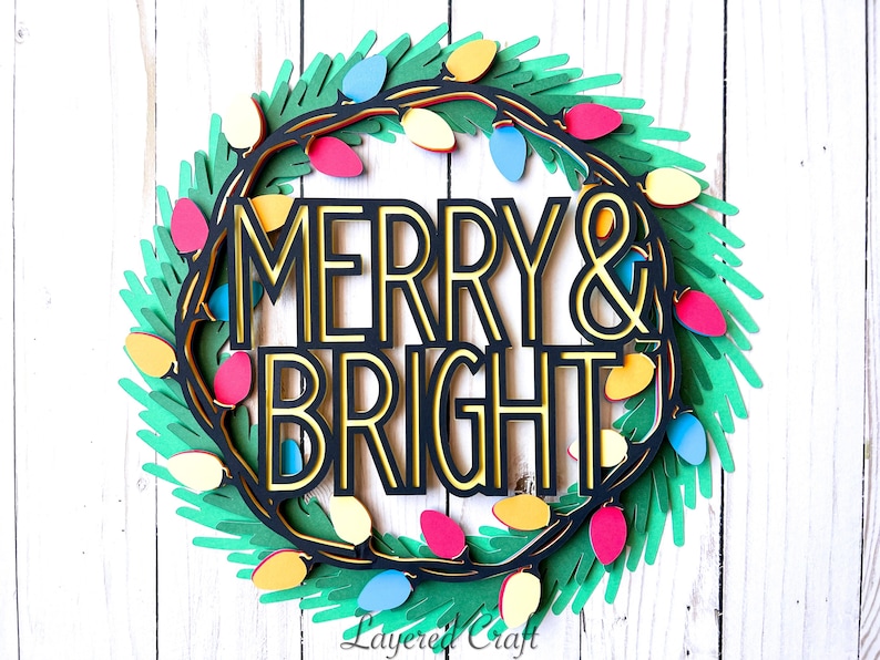 Pu&ograve; includere: Una ghirlanda natalizia di carta a strati con le parole "MERRY & BRIGHT" in nero e oro. La ghirlanda &egrave; decorata con luci colorate e fogliame verde, perfetta per le decorazioni natalizie.