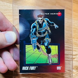 May include: A Marvel Super Heroes trading card featuring Nick Fury in a dynamic pose. The card has a red border and the Marvel 1992 logo. The background is a mix of green and blue, with the text "NICK FURY" at the bottom.