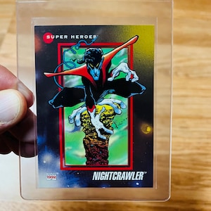 May include: A Nightcrawler trading card from Marvel's 1992 Super Heroes series. The card features a dynamic illustration of Nightcrawler in a black and blue costume, with red accents, set against a colorful background. The card is encased in a clear protective sleeve.