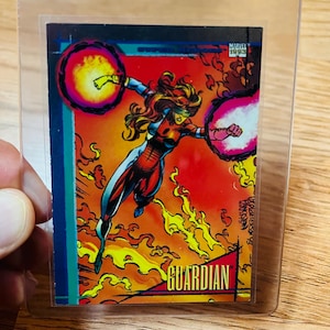May include: A Marvel 1993 trading card featuring the character Guardian. The card shows a female superhero in a dynamic pose, surrounded by flames and energy spheres. The card is encased in a clear protective sleeve.