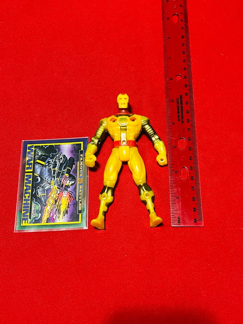 May include: Yellow and black action figure of War Machine from the Marvel Comics universe. The figure is posed standing with its arms outstretched. The figure is approximately 4 inches tall. The figure is packaged with a card featuring a comic book image of War Machine.