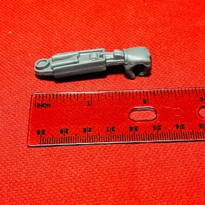 May include: A gray plastic toy arm with a hand, featuring a detailed design with multiple joints. The arm is approximately 2 inches long.