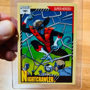 May include: A 1991 Marvel Super Heroes trading card featuring Nightcrawler. The card has a yellow background with a comic book illustration of Nightcrawler in action, with the word "NIGHTCRAWLER" in yellow.