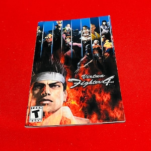 May include: A video game instruction manual for Virtua Fighter 4, featuring a character with a white headband and a red background with flames. The ESRB rating of "Teen" is visible on the front cover.
