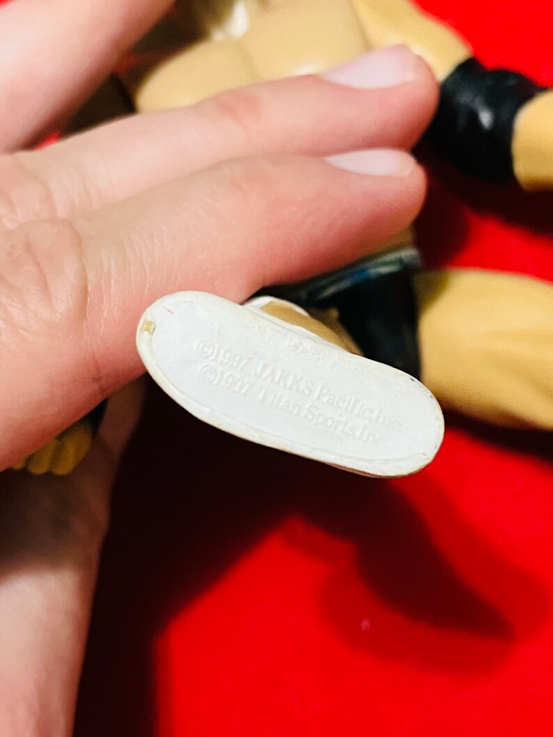 May include: White plastic foot of an action figure with the text "1997 Jakks Pacific, Inc. 1997 Titan Sports, Inc." printed on the bottom.