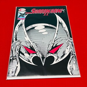 May include: A comic book cover featuring a black and white illustration of a character with red eyes. The title "SHADOWHAWK II" is printed in white on a black background. The comic book is published by Image.