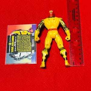 May include: Yellow and red plastic action figure of War Machine from the Marvel Comics universe. The figure is approximately 6 inches tall and has a card with information about the character.