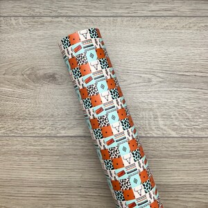 May include: A roll of patterned wrapping paper with a patchwork design featuring turquoise, orange, brown, and black geometric shapes, animal prints, and cactus silhouettes.