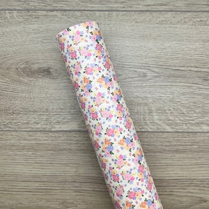 May include: A roll of white faux leather with a floral pattern featuring pink, orange, and purple flowers. The flowers are scattered across the fabric.