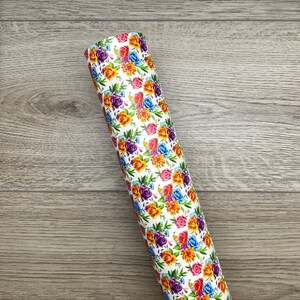May include: A roll of white vinyl with a floral pattern featuring colourful roses, purple flowers, and green leaves.