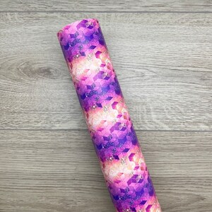 May include: A roll of purple and pink patterned vinyl with a geometric design. The vinyl has a glittery finish.