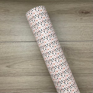 May include: A roll of white wrapping paper with a repeating pattern of small, colorful dots and dashes. The dots are in shades of pink, orange, brown, and black.