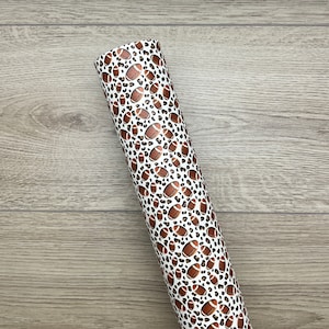 May include: A roll of white vinyl with a brown and black leopard print and copper footballs.