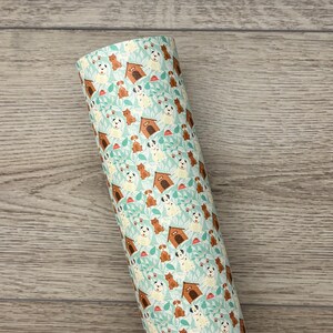 May include: A roll of white vinyl with a repeating pattern of brown and white dogs, dog houses, and green leaves on a light blue background.