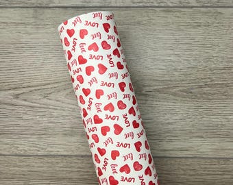 May include: A roll of white wrapping paper with a repeating pattern of red hearts and the word "LOVE" printed in blue.