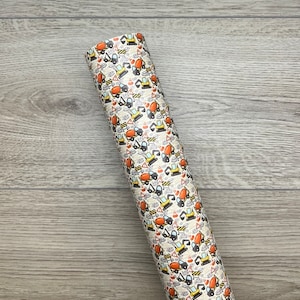 May include: A roll of white vinyl with a repeating pattern of construction vehicles and tools. The vehicles are yellow and orange with black details. The tools are grey and black.