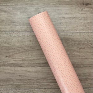 May include: A roll of pink wrapping paper with a white polka dot pattern.