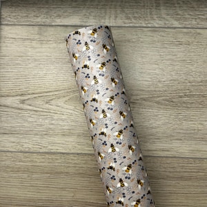 May include: A close-up of a fabric with a repeating pattern of bees and honeycomb on a light gray background. The bees are yellow and black with brown wings.
