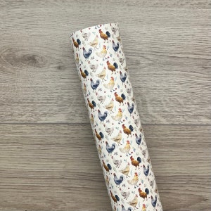 May include: A white roll of vinyl with a repeating pattern of colorful roosters and hens. The roosters and hens are illustrated in a watercolor style.