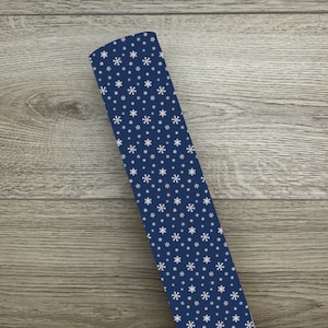 May include: A roll of blue wrapping paper with a white snowflake pattern.