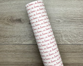May include: A roll of white wrapping paper with a repeating pattern of red hearts and the word "love" written in cursive.