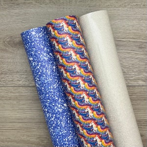 May include: Three rolls of patterned vinyl for crafting projects. One roll features a blue glitter pattern, another has a white glitter pattern, and the third has a repeating pattern of unicorns and rainbows on a blue background.
