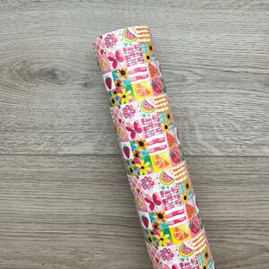 May include: A roll of pink and white patterned wrapping paper with a patchwork design featuring watermelons, lemons, butterflies, and flowers.