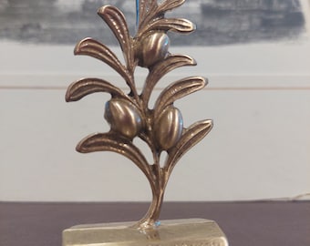 May include: A gold-colored metal olive branch figurine with three olives on the branches. The base of the figurine is inscribed with the words "Olive Branch".