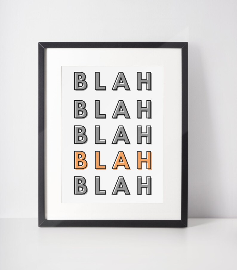 May include: A framed print with the word "BLAH" repeated five times in a vertical column. The word "BLAH" is in a gray font with a black outline, except for the third "BLAH" which is in an orange font with a gray outline.