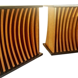 May include: Two wooden side tables with a unique design. Each table features a curved, light-colored wood frame with vertical, wavy slats. The base and top are dark brown, creating a contrast. The tables are placed side by side.
