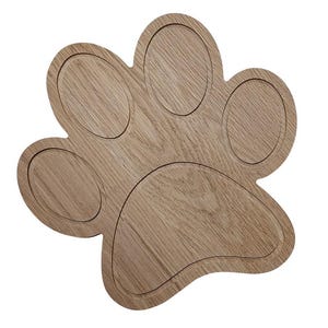 Puede incluir: Bandeja de madera en forma de pata, de color marrón claro. Cuenta con cinco hendiduras circulares para colocar objetos pequeños. Un accesorio decorativo para amantes de las mascotas, que añade un toque lúdico.