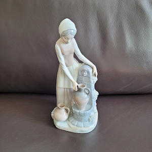 Vintage porcelain figurine of girl at fountain, marked NAO Spain (Lladro)