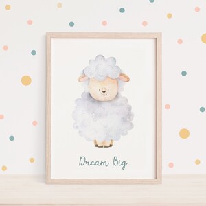 Pu&ograve; includere: Un'illustrazione ad acquerello di una pecora bianca su uno sfondo blu chiaro. La pecora &egrave; in piedi su una superficie bianca e il testo "Dream Big" &egrave; scritto sotto la pecora in blu chiaro.