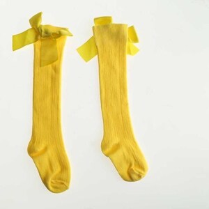 May include: A pair of yellow knee-high socks with yellow bows at the top.