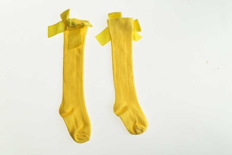 May include: A pair of yellow knee-high socks with yellow bows at the top.