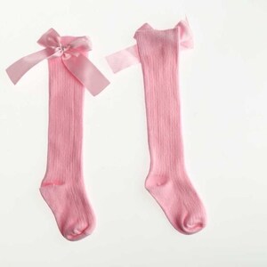 May include: A pair of pink knee-high socks with a pink satin bow at the top.