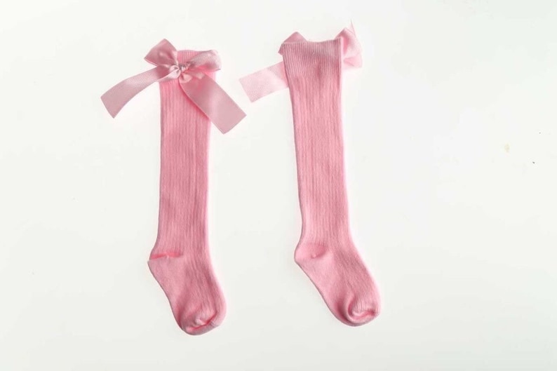 May include: A pair of pink knee-high socks with a pink satin bow at the top.