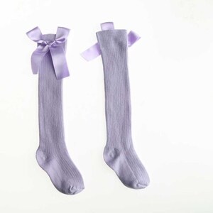 May include: A pair of lavender knee-high socks with a satin bow at the top.