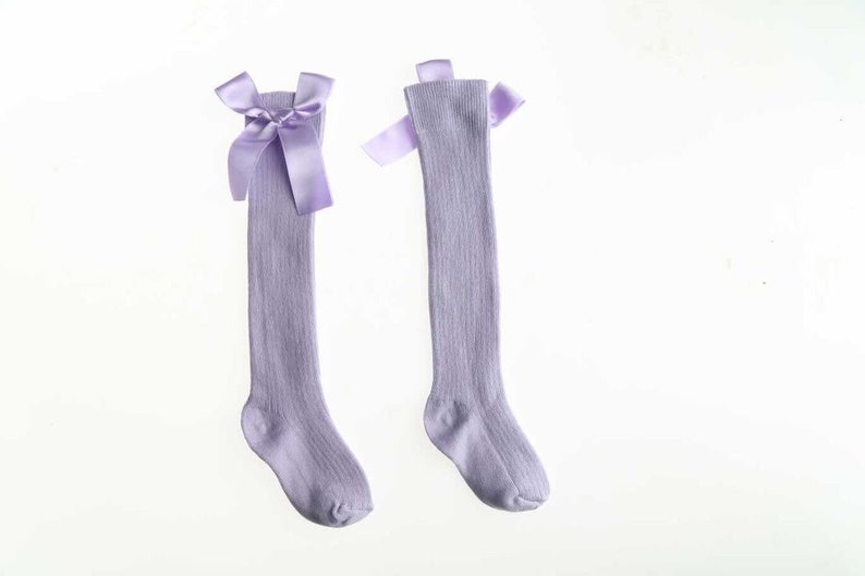 May include: A pair of lavender knee-high socks with a satin bow at the top.