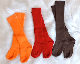 May include: Three pairs of knee-high socks in orange, red, and brown. The socks are ribbed and have a casual look.